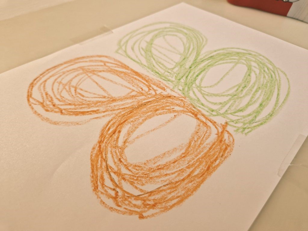 Niño practicando dibujo bilateral con ambas manos de forma simétrica sobre papel